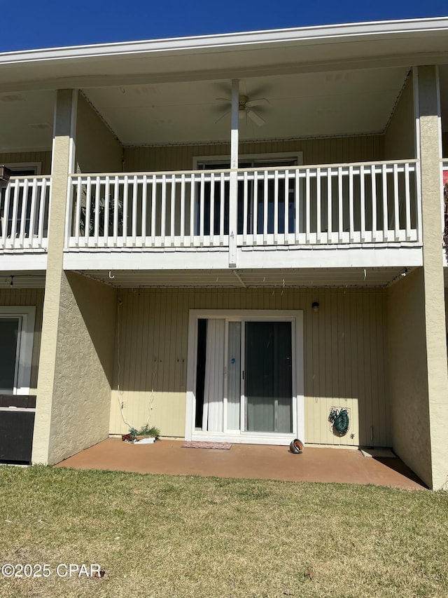 rear view of house with a balcony, ceiling fan, a lawn, and a patio