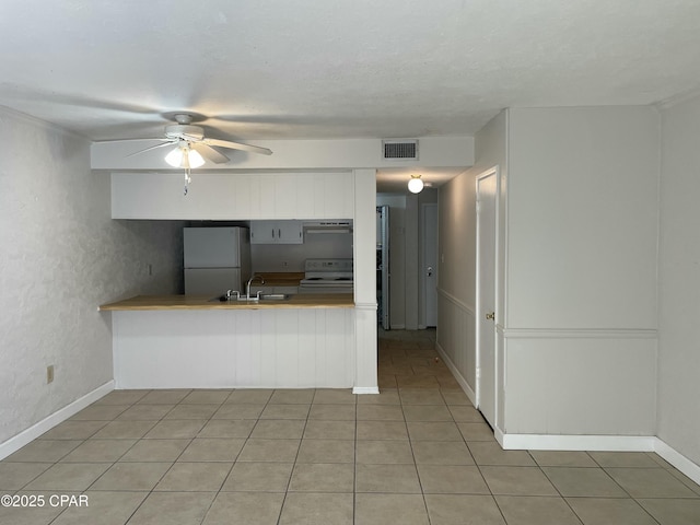 kitchen featuring white range with electric cooktop, visible vents, freestanding refrigerator, a sink, and a peninsula