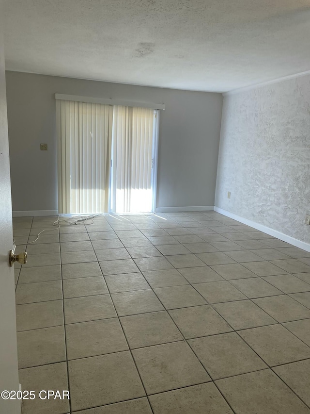 unfurnished room with light tile patterned flooring, baseboards, a textured ceiling, and a textured wall