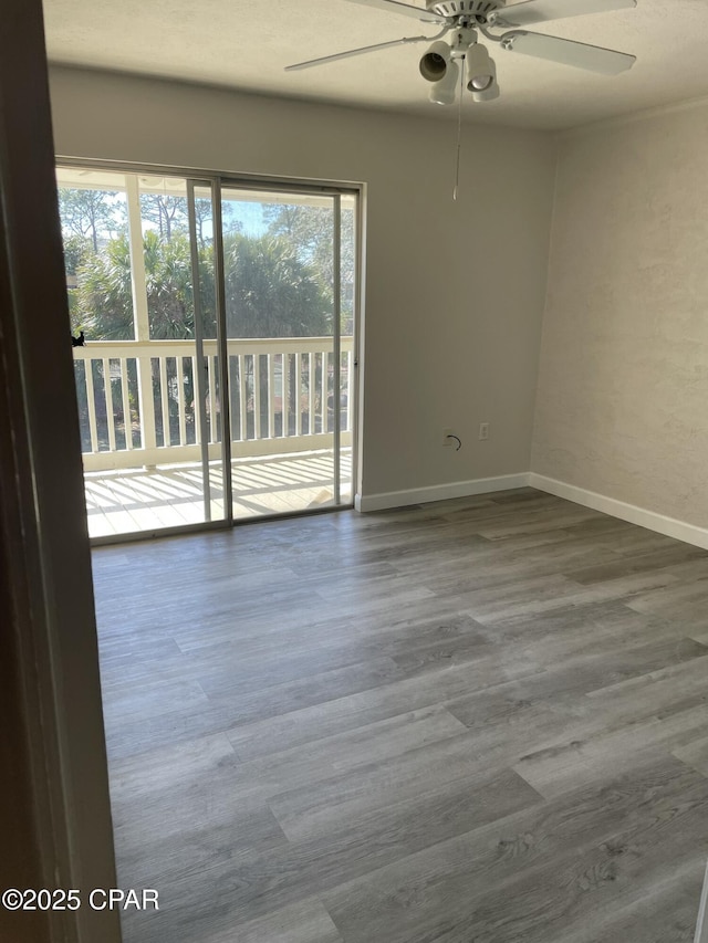 empty room with ceiling fan, baseboards, and wood finished floors