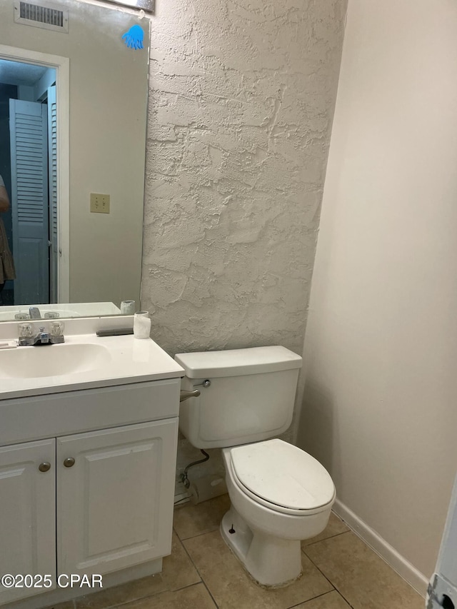 half bathroom with toilet, vanity, visible vents, and tile patterned floors