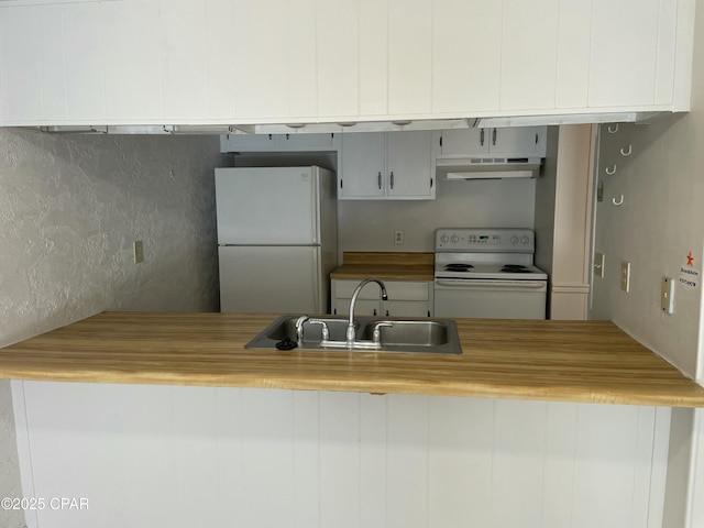 kitchen with white appliances, a sink, under cabinet range hood, and wood counters