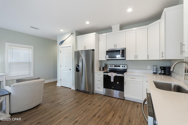 kitchen featuring a sink, dark wood-type flooring, light countertops, appliances with stainless steel finishes, and white cabinetry