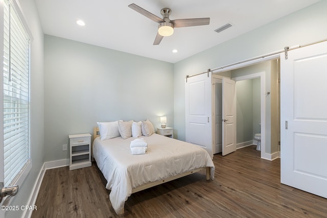 bedroom featuring recessed lighting, baseboards, a barn door, and wood finished floors