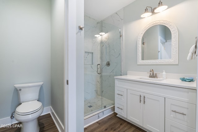 full bathroom featuring a marble finish shower, baseboards, toilet, wood finished floors, and vanity