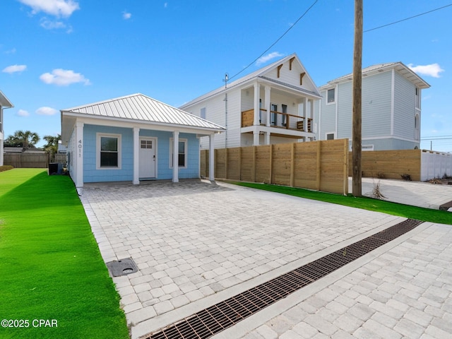 exterior space featuring metal roof, a front lawn, and fence