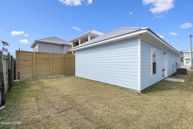 exterior space featuring metal roof, a lawn, central AC unit, and fence