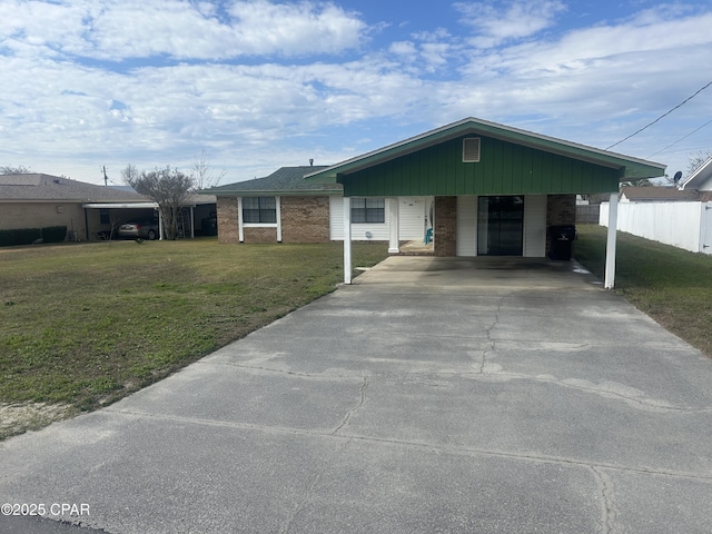 ranch-style home featuring driveway, an attached carport, fence, a front lawn, and brick siding