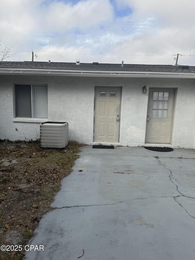 view of exterior entry with central air condition unit and a patio area