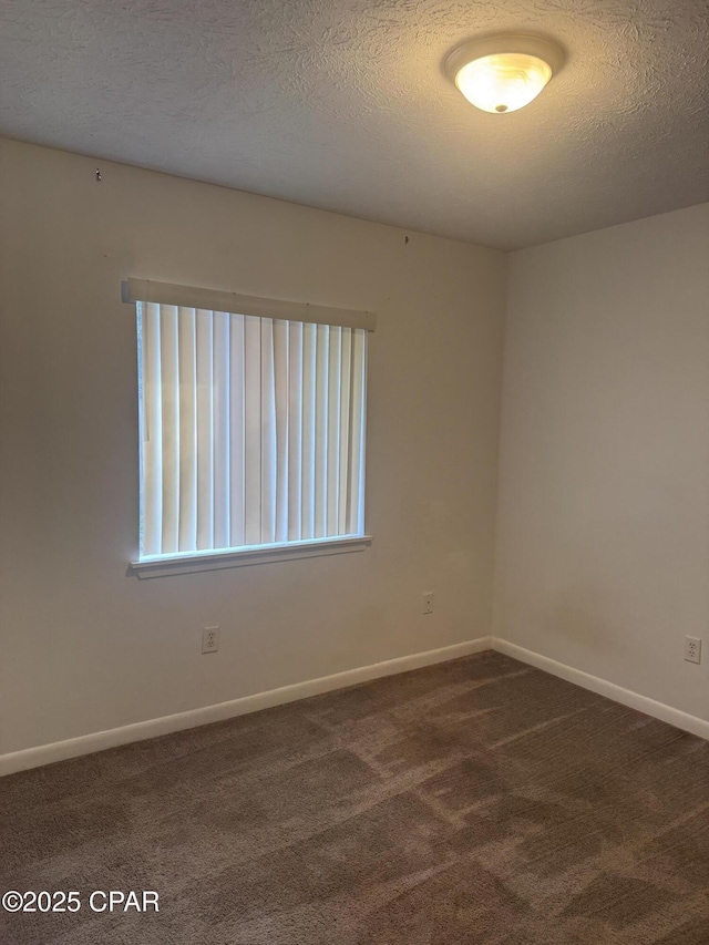 unfurnished room featuring dark carpet and a textured ceiling