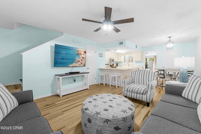 living room with ceiling fan and light wood-type flooring