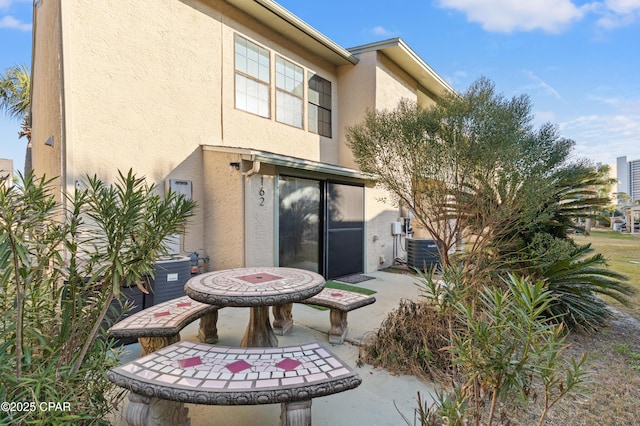 rear view of house with central AC unit and a patio