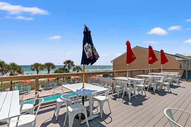 wooden deck with a water view, a community pool, and a view of the beach