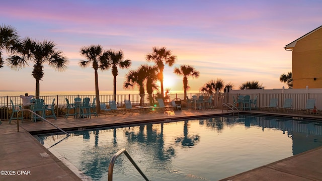 pool at dusk with a water view and a patio