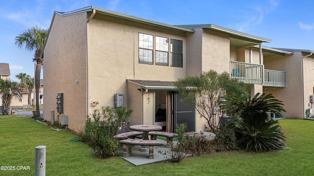 back of property featuring a lawn and a balcony