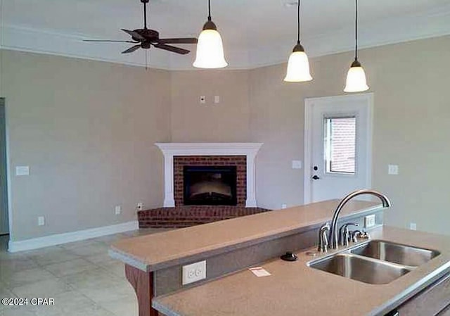 kitchen with open floor plan, decorative light fixtures, light countertops, a fireplace, and a sink