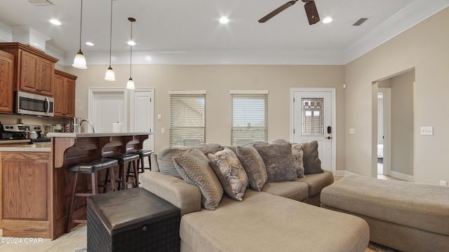 living room with ceiling fan, light tile patterned floors, visible vents, a healthy amount of sunlight, and ornamental molding