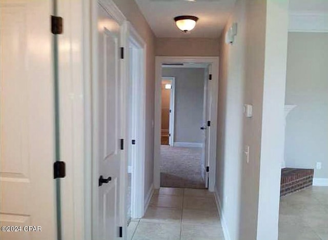 hallway featuring light tile patterned floors and baseboards