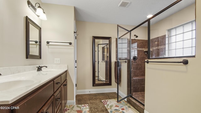 full bath featuring double vanity, visible vents, a sink, and tiled shower