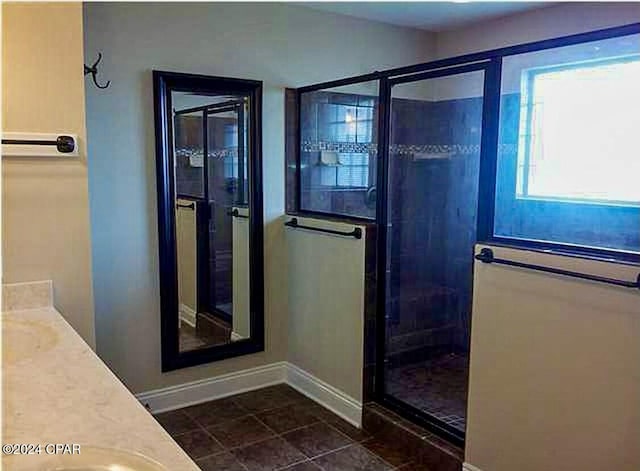 full bathroom featuring a stall shower, vanity, baseboards, and tile patterned floors