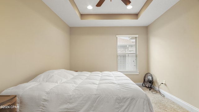 carpeted bedroom featuring a tray ceiling, ceiling fan, baseboards, and recessed lighting