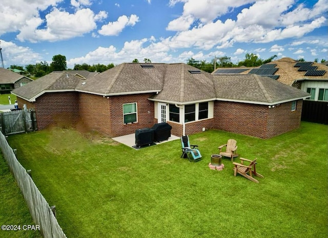 back of house featuring an outdoor fire pit, a lawn, a fenced backyard, and brick siding