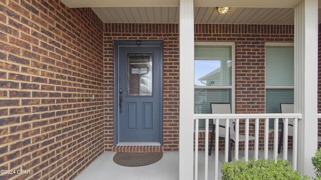 property entrance featuring a porch and brick siding