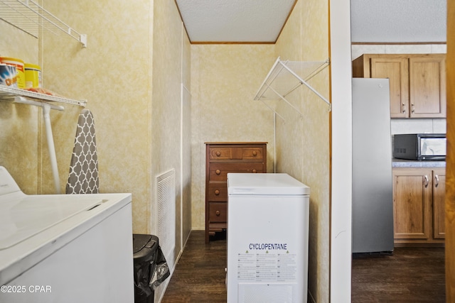 laundry area with crown molding, a textured ceiling, washer and dryer, laundry area, and dark wood-style floors