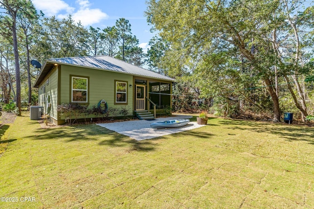 rear view of house with a patio, a yard, a sunroom, and central AC