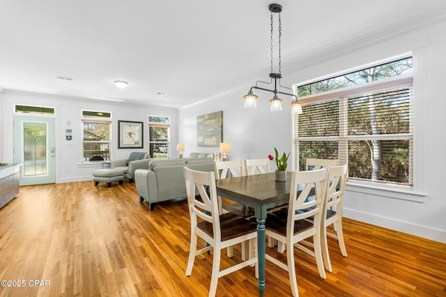 dining room with plenty of natural light, light wood-style flooring, baseboards, and crown molding