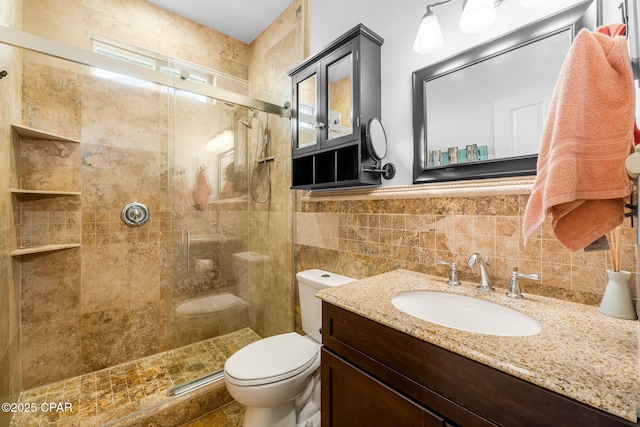 full bathroom featuring a stall shower, vanity, toilet, and tile walls