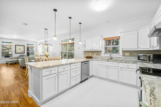 kitchen featuring appliances with stainless steel finishes, white cabinets, a peninsula, and decorative light fixtures