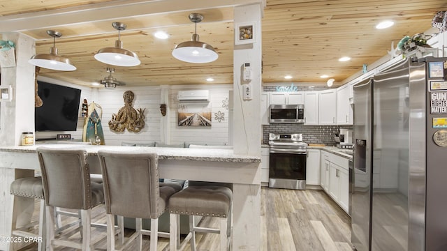 kitchen featuring a breakfast bar area, wood ceiling, white cabinets, appliances with stainless steel finishes, and a wall mounted air conditioner