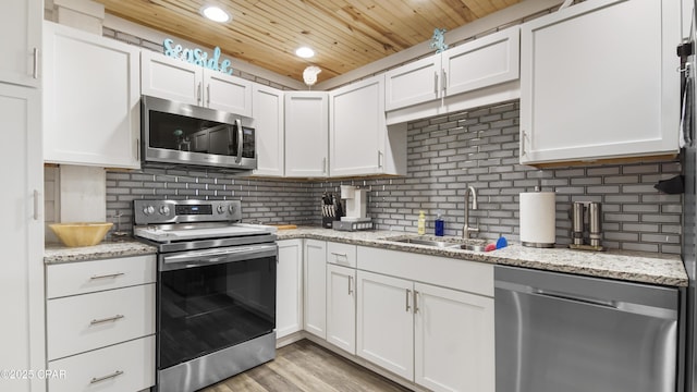 kitchen with stainless steel appliances, backsplash, white cabinets, a sink, and wooden ceiling