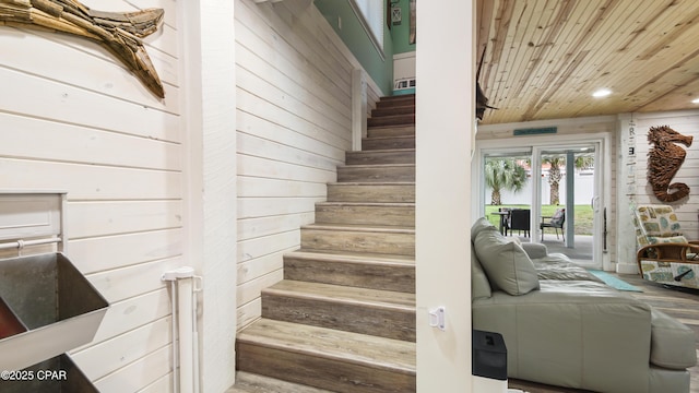 stairs with wooden ceiling, wooden walls, and recessed lighting