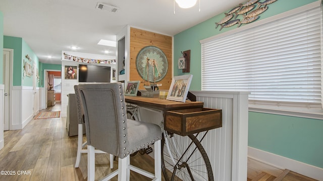 interior space with wainscoting, wood finished floors, and visible vents