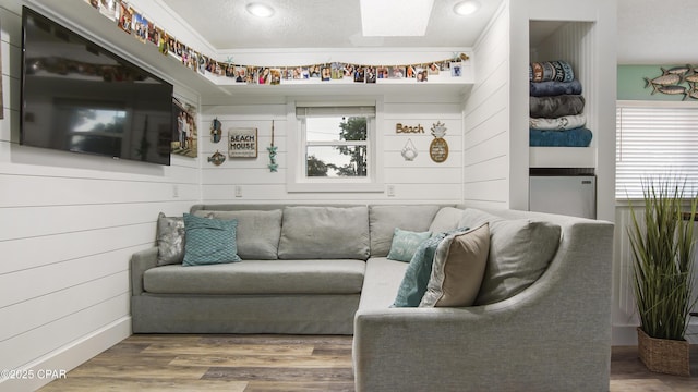 living room featuring a skylight, a textured ceiling, and wood finished floors