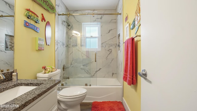 bathroom featuring toilet, enclosed tub / shower combo, vanity, wood finished floors, and baseboards