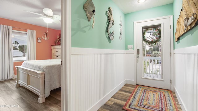 doorway to outside featuring a wainscoted wall, a textured ceiling, plenty of natural light, and wood finished floors