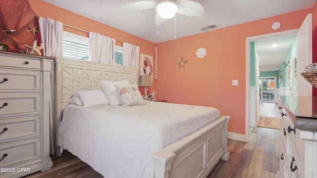 bedroom with multiple windows, wood finished floors, visible vents, and baseboards