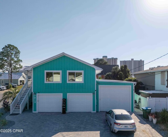 garage with decorative driveway and fence