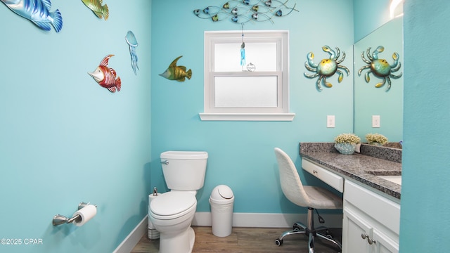 bathroom featuring toilet, baseboards, wood finished floors, and vanity