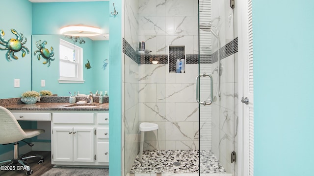 full bath with a marble finish shower, wood finished floors, and vanity