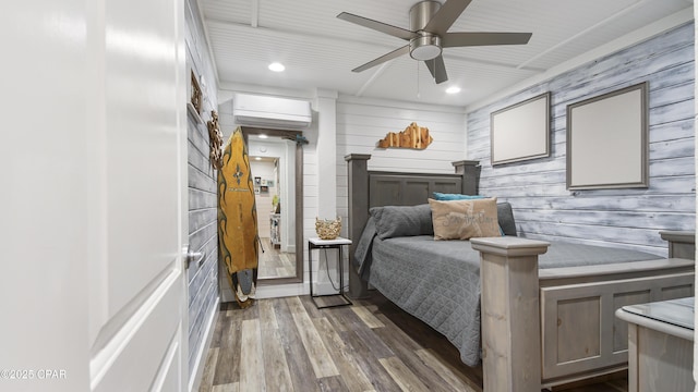 bedroom with ceiling fan, an AC wall unit, wood finished floors, and recessed lighting