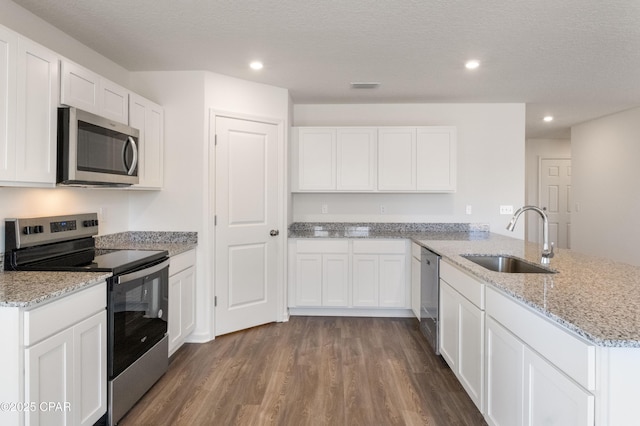 kitchen with visible vents, a peninsula, dark wood-style flooring, a sink, and appliances with stainless steel finishes