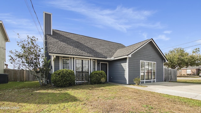 ranch-style home with fence, a front lawn, and roof with shingles