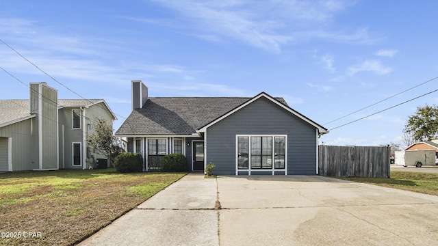 view of front of home featuring a shingled roof, a chimney, a front yard, and fence