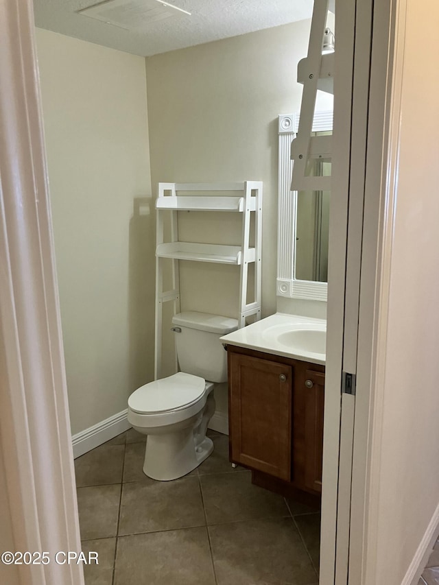 half bath with tile patterned floors, toilet, vanity, and baseboards