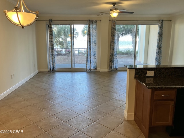 interior space featuring a ceiling fan, ornamental molding, baseboards, and a wealth of natural light