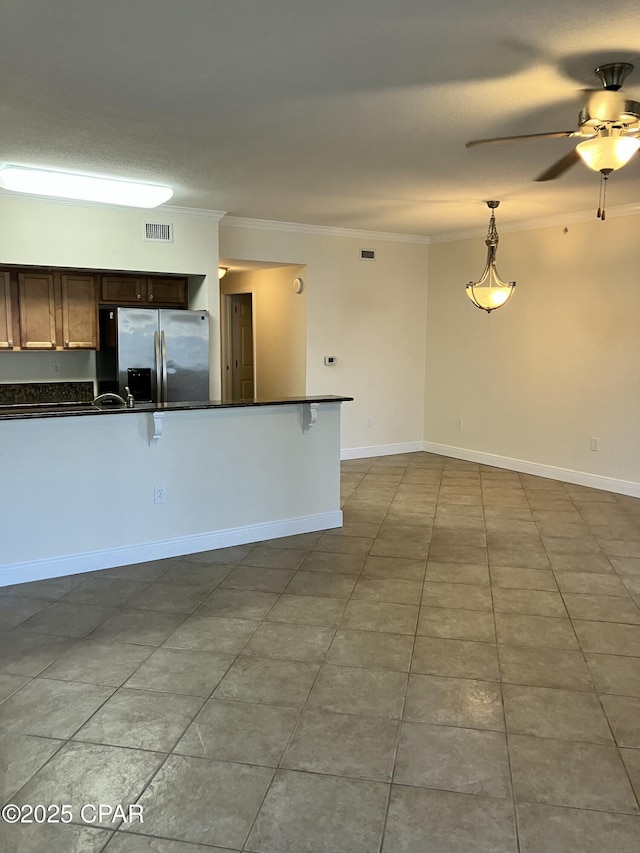 kitchen with stainless steel fridge, dark countertops, visible vents, ceiling fan, and ornamental molding